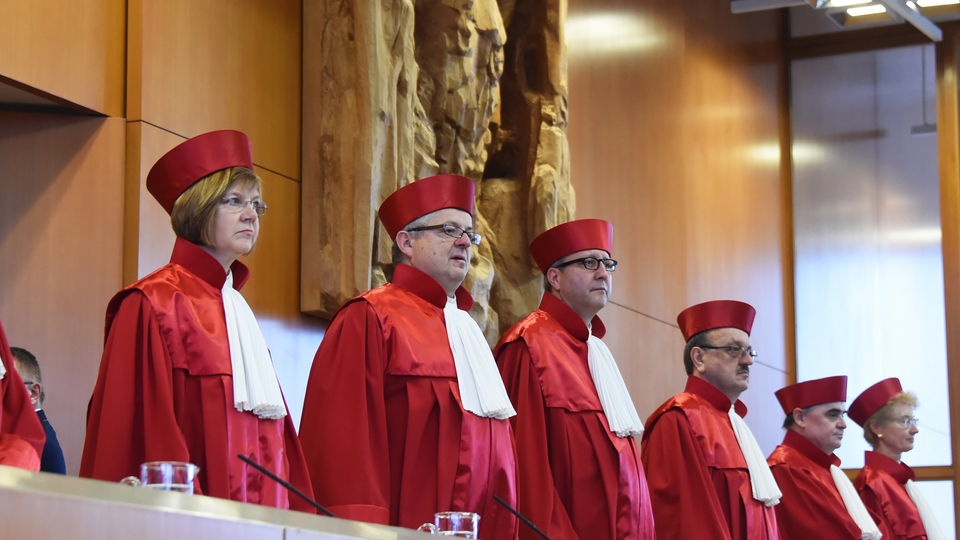 Acht Richter des Bundesverfassungsgerichts stehen in roten Roben nebeneinander.