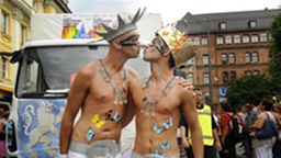 Zwei verkleidete Männer in einer Parade küssen sich..