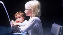 Ein Kind und ein Erwachsener sitzen an einem Computer