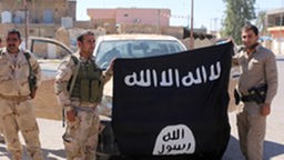Kurdische Kämpfer halten eine Flagge des IS.