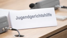 Ein Schild mit der Aufschrift "Jugendgerichthilfe" steht in einem Verhandlungsraum auf dem Tisch.