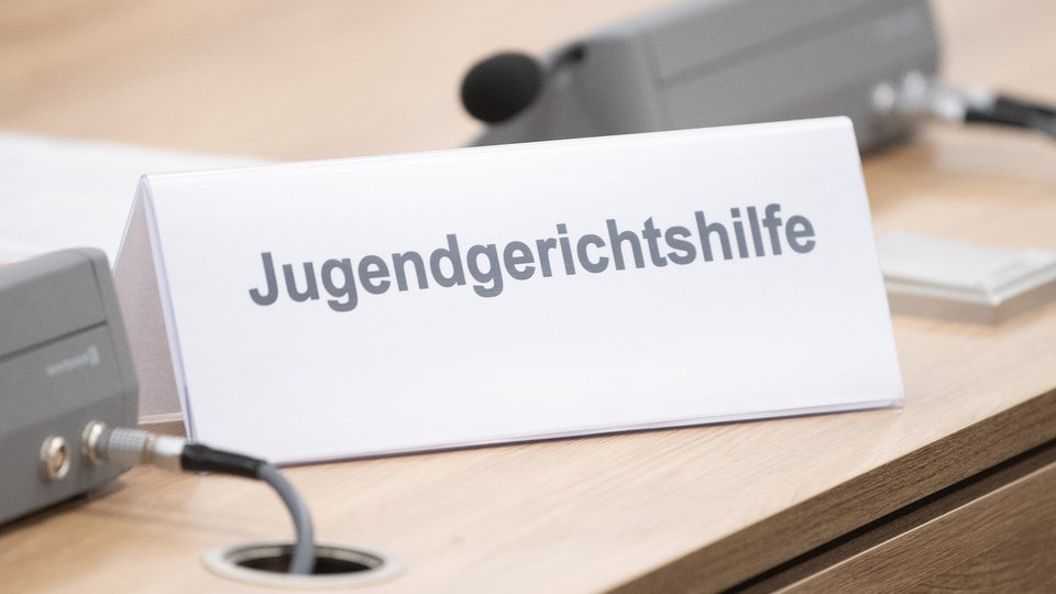 Ein Schild mit der Aufschrift "Jugendgerichthilfe" steht in einem Verhandlungsraum auf dem Tisch.