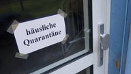 Schild an einer Tür mit der Aufschrift 'häusliche Quarantäne'.