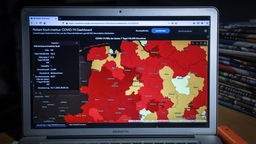 Deutschlandkarte auf einem Monitor, in denen Regionen mit einem hohen Inzidenzwert in verschiedenen Rottönen eingefärbt sind. 