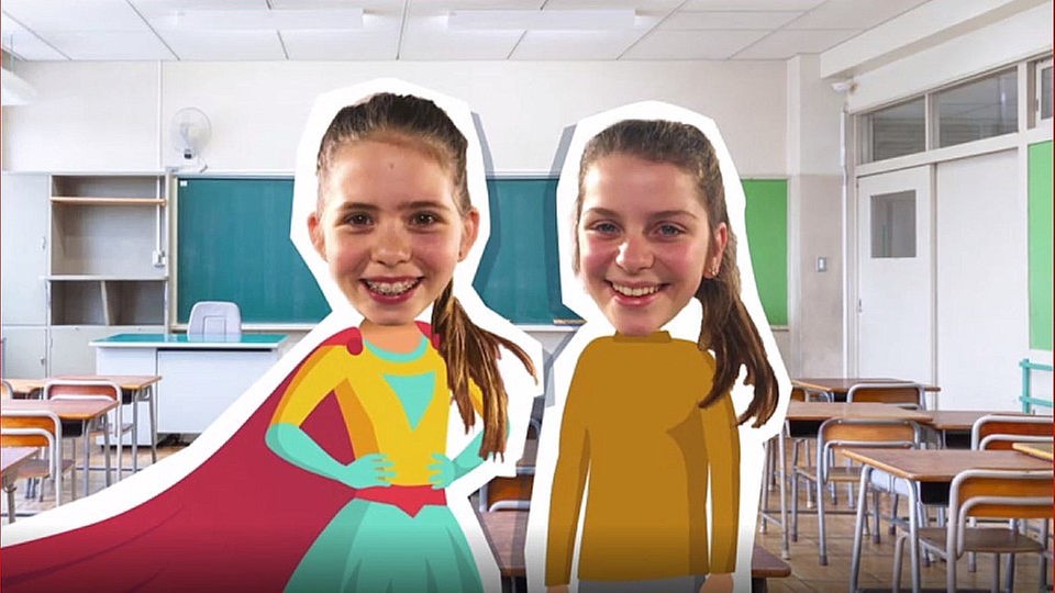 Zwei Mädchen stehen in Schulklasse nebeneinander, Eine trägt ein Supergirl-Kostüm (Animation).