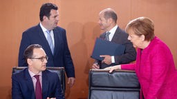 Kanzlerin Angela Merkel spricht mit Heiko Maas, im Hintergrund Hubertus Heil und Olaf Scholz.