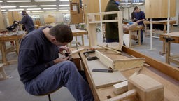Jugendlicher arbeitet in einer Werkstatt mit Holz.