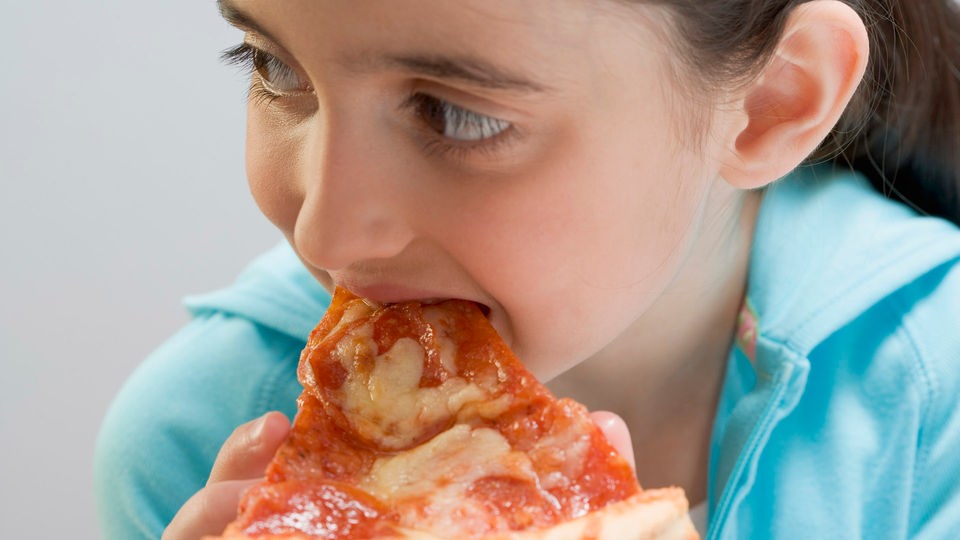 Mädchen isst Pizza.