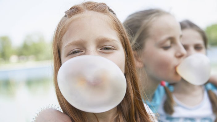 Drei Mädchen mit großer Kaugummiblase vor dem Mund