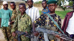 Afrikanische Jungen halten Maschinengewehre.