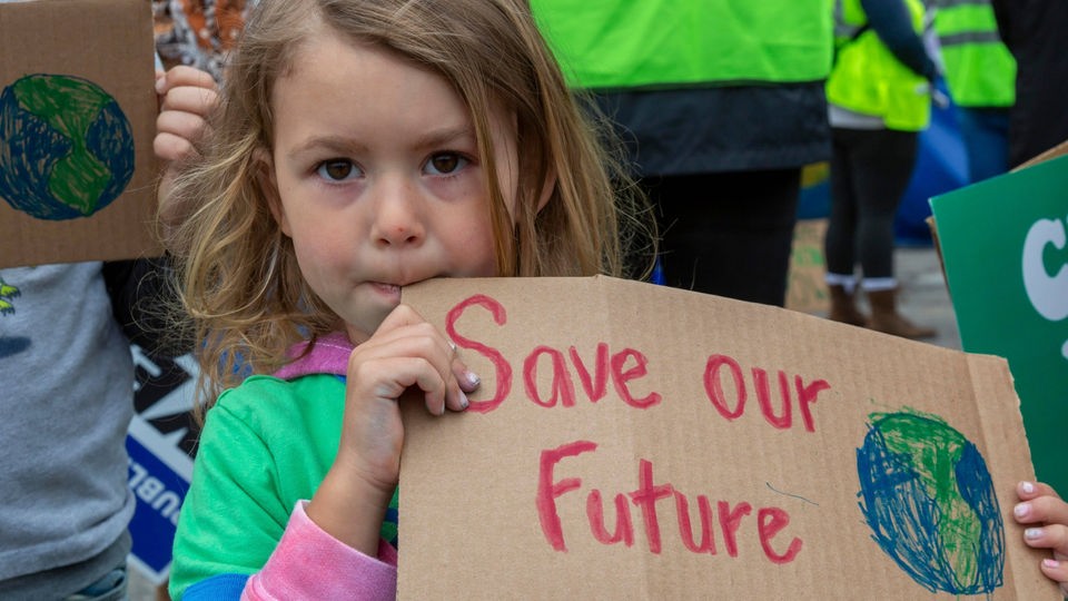 US-Amerikanisches Mädchen hält Schild mit Aufschrift 'Save our future'.