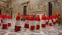 Eine Gruppe von Kardinälen in roten Umhängen betritt einen Raum der Sixtinischen Kapelle