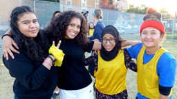 Schülerinnen unterschiedlicher Herkunft, mit und ohne Kopftuch, posieren für Kamera.