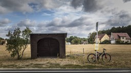 Ein Fahrrad steht an einer Bushaltestelle in einer ländlichen Region.