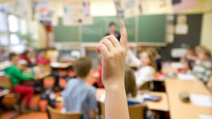 Ein Schüler meldet sich im Unterricht mit Handzeichen.