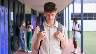 Ein Schüler läuft über den Schulhof. Im Hintergrund sind unscharf weitere Schülerinnen und Schüler erkennbar.