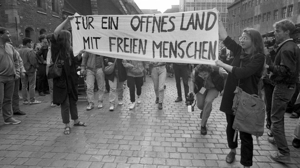 1989: Demonstrantinnen in Leipzig tragen ein Transparent mit der Aufschrift "Für ein offenes Land mit freien Menschen".