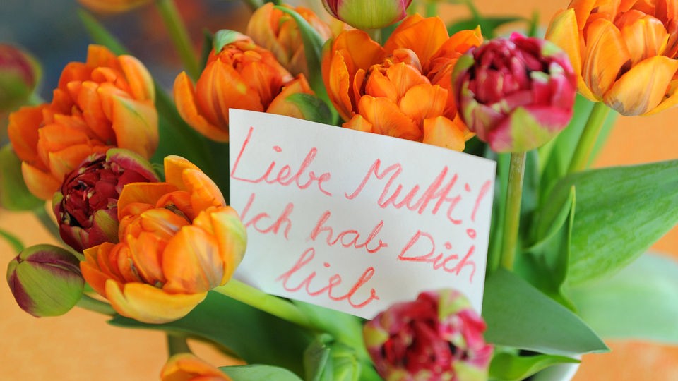 Ein Zettel in einem Blumenstrauß mit dem Text "Liebe Mutti! Ich hab Dich lieb".