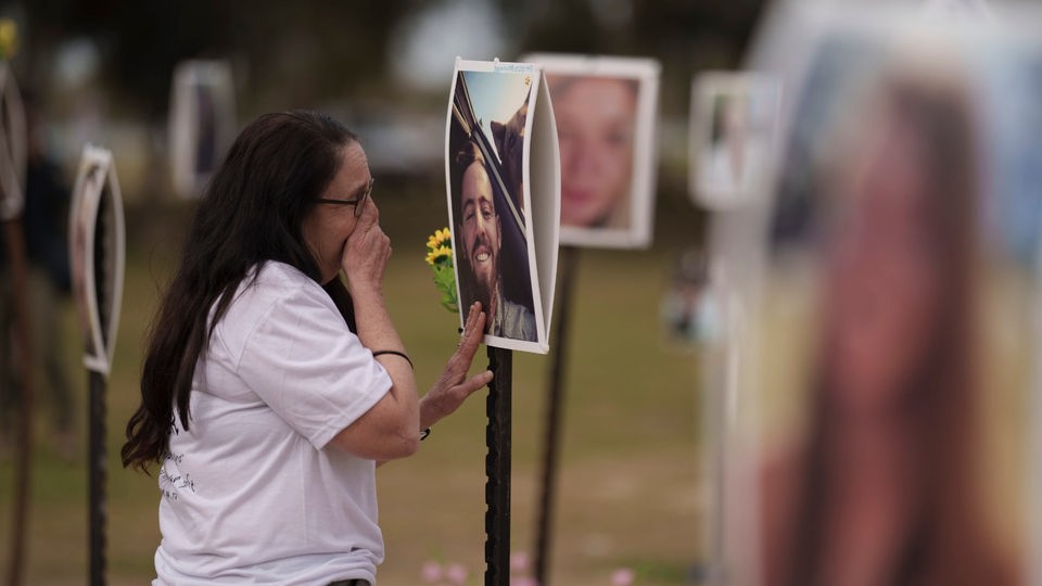 Eine Frau steht weinend vor dem Foto ihres ermordeten Sohnes.
