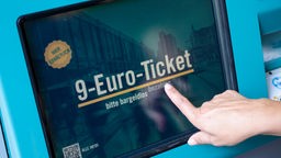Hand tippt auf Anzeige '9-Euro-Ticket' auf Monitor.
