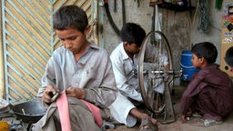 Drei kleine Jungen arbeiten in einer Fahrradreparaturwerkstatt.
