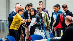 Eine Frau zeigt Flüchtlingen, wo sie sich registrieren lassen können.