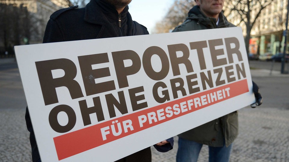 Zwei Männer halten ein Plakat mit der Aufschrift "Reporter ohne Grenzen für Pressefreiheit".