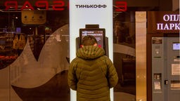 Ein Mann hebt an einem Geldautomaten in Moskau russische Rubel ab.
