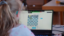 Ein Mädchen spielt online Schach. 