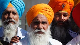 Männliche Sikhs mit verschiedenfarbigen Turbanen nebeneinander.