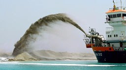 Ein Schiff pumpt Sand auf die entstehende Palminsel vor Dubai.
