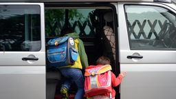 Zwei Kinder steigen in einen Transporter.