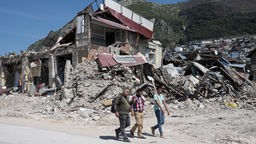 Mit einer Schaufel laufen Anwohner an Trümmern der Altstadt von Antakya vorbei.