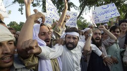 Taliban-Anhänger demonstrieren gegen möglich US-Angriffe und halten Schilder mit arabischer Schrift in Händen