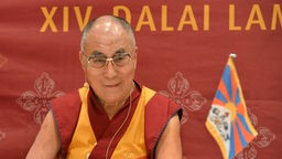 Der Dalai Lama lächelt in die Kamera.