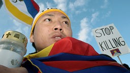 Ein Exiltibeter mit einer umgebundenen tibetischen Fahne und einer Kerze.
