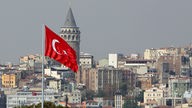 Blick auf Istanbul mit dem Galata-Turm, der halb verdeckt ist durch eine türkische Flagge.