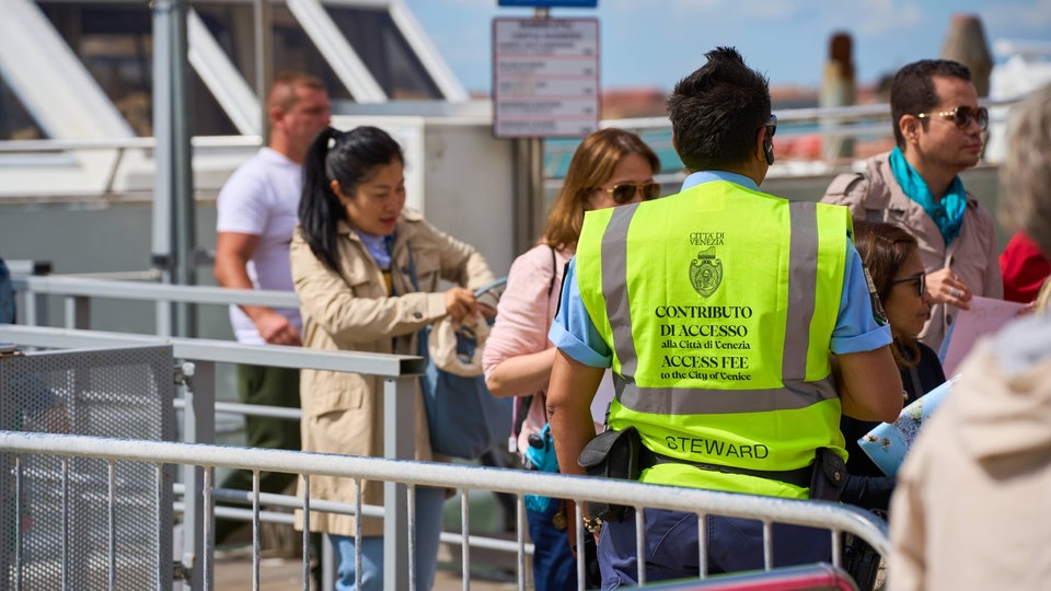 Kontrolleur in gelber Weste kassiert Geld von Touristen, die Schiff verlassen.