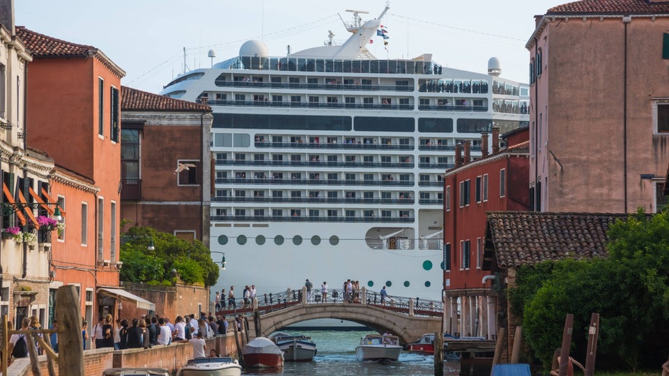 Riesiges Kreuzfahrtschiff hinter Brücke in Venedig.