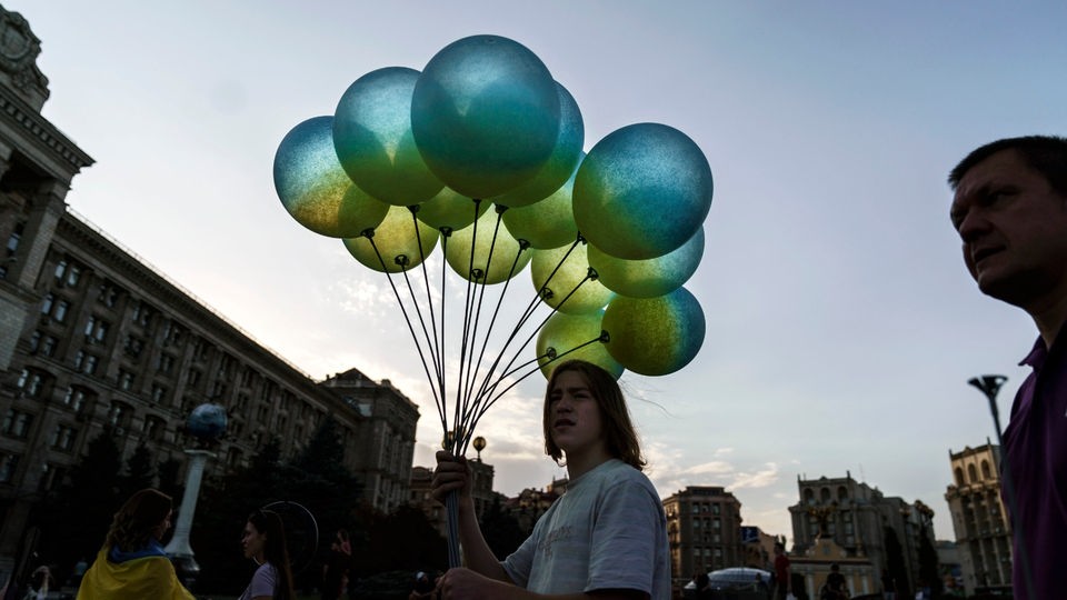 Eine Frau hält Luftballons in den ukrainischen Landesfarben.
