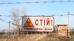 Schild mit kyrillischer Schrift und dem Zeichen für Radioaktivität.