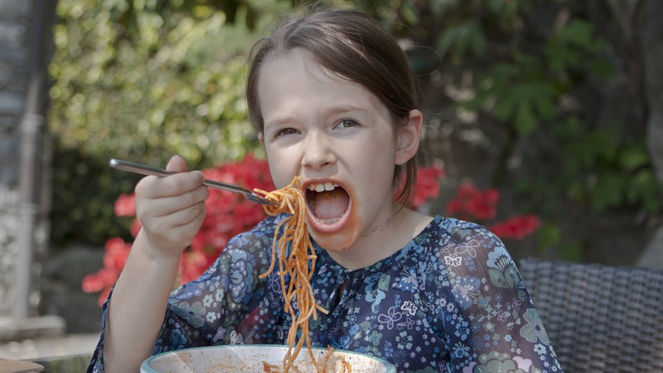 Mädchen isst Spaghetti.