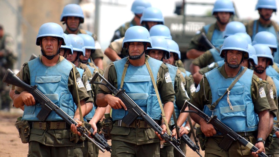 Eine Gruppe Blauhelm-Soldaten marschiert mit Gewehren.