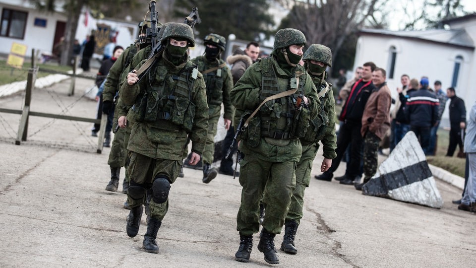 2014: Schwerbewaffnete russische Soldaten verlassen eine eroberte ukrainische Militärbasis auf der Krim. 