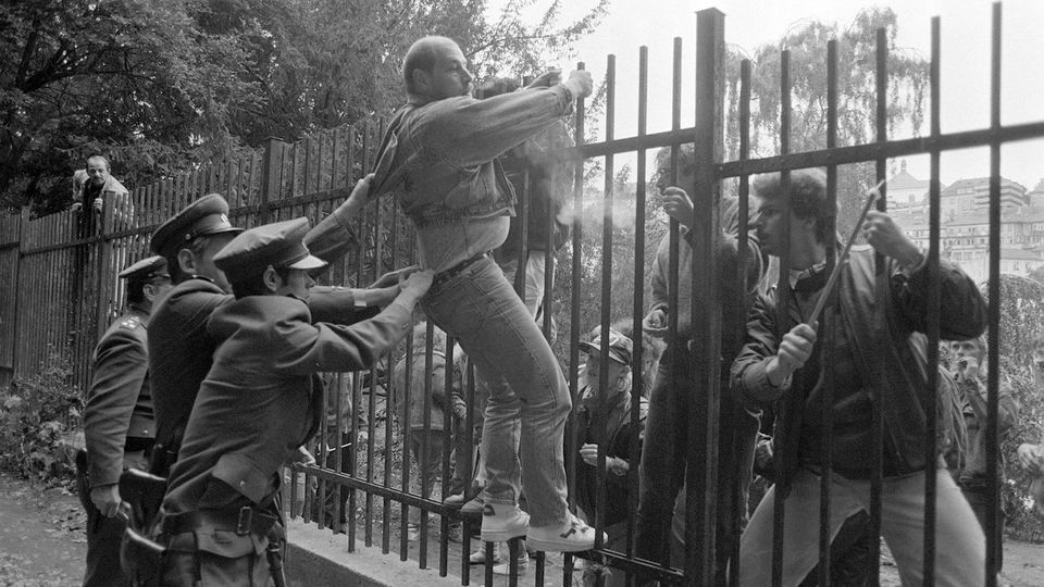 DDR-Bürger versucht über den Zaun der deutschen Botschaft in Prag zu klettern. Tschechoslowakische Polizisten halten ihn fest.
