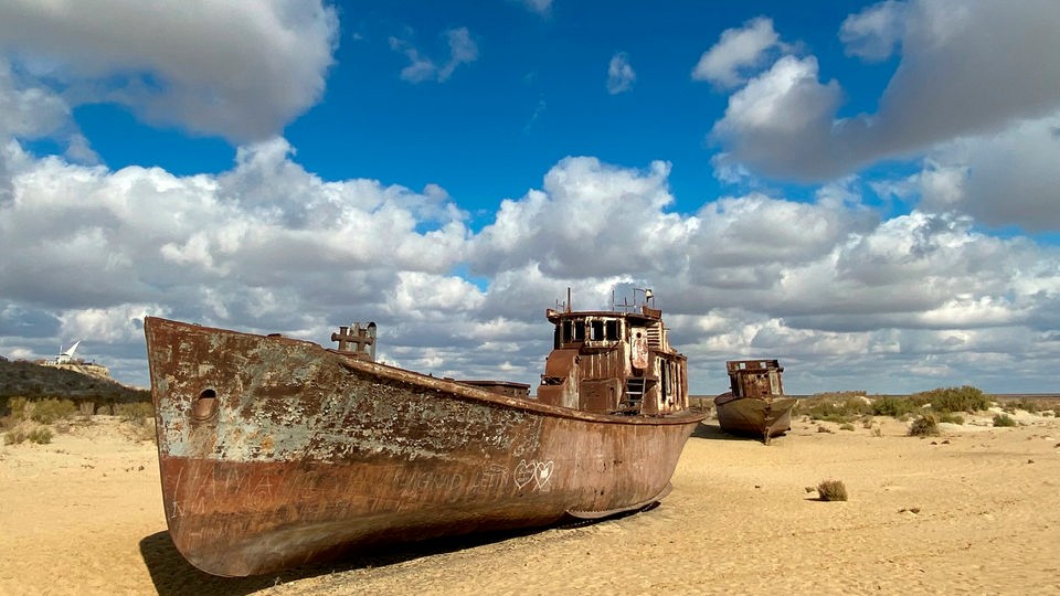 Rostige Schiffe liegen im Sand.