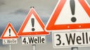 Warnende Verkehrsschilder mit Aufschrift "Dritte Welle", "Vierte Welle" und "Fünfte Welle".