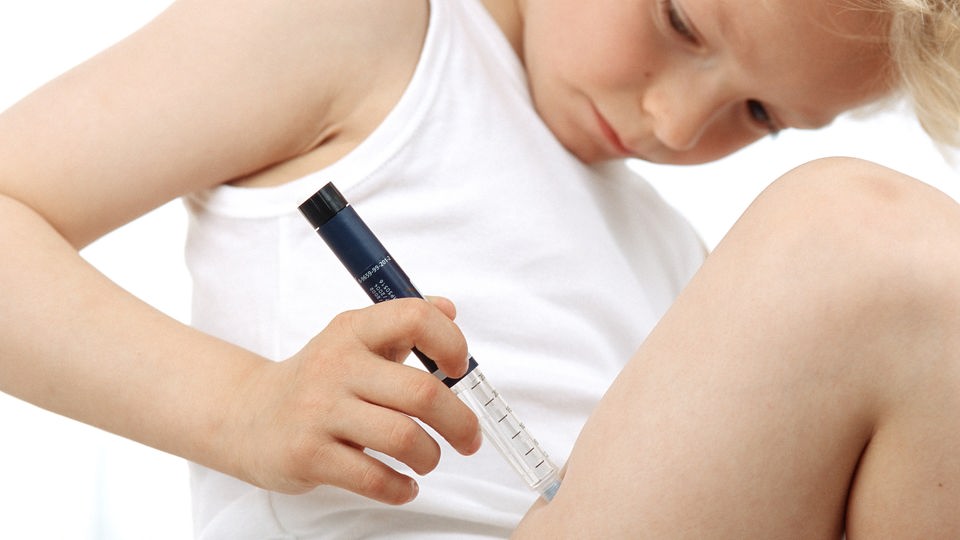 Junge setzt sich eine Insulin-Spritze ins Bein.