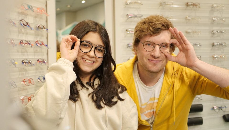 Melody und Robert posieren mit ihren Brillen in einem Brillengeschäft.