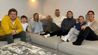 Robert sitzt mit einer siebenköpfigen Patchworkfamilie auf einem großen Sofa.